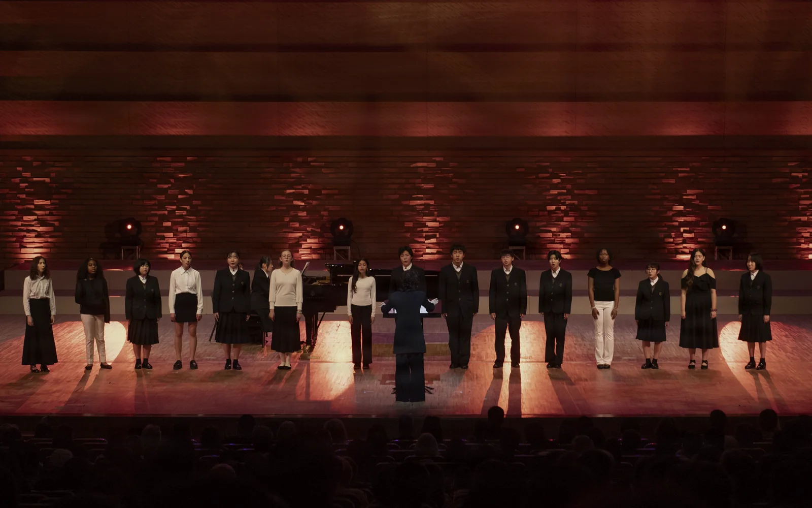A student chorus performing together on a concert stage.