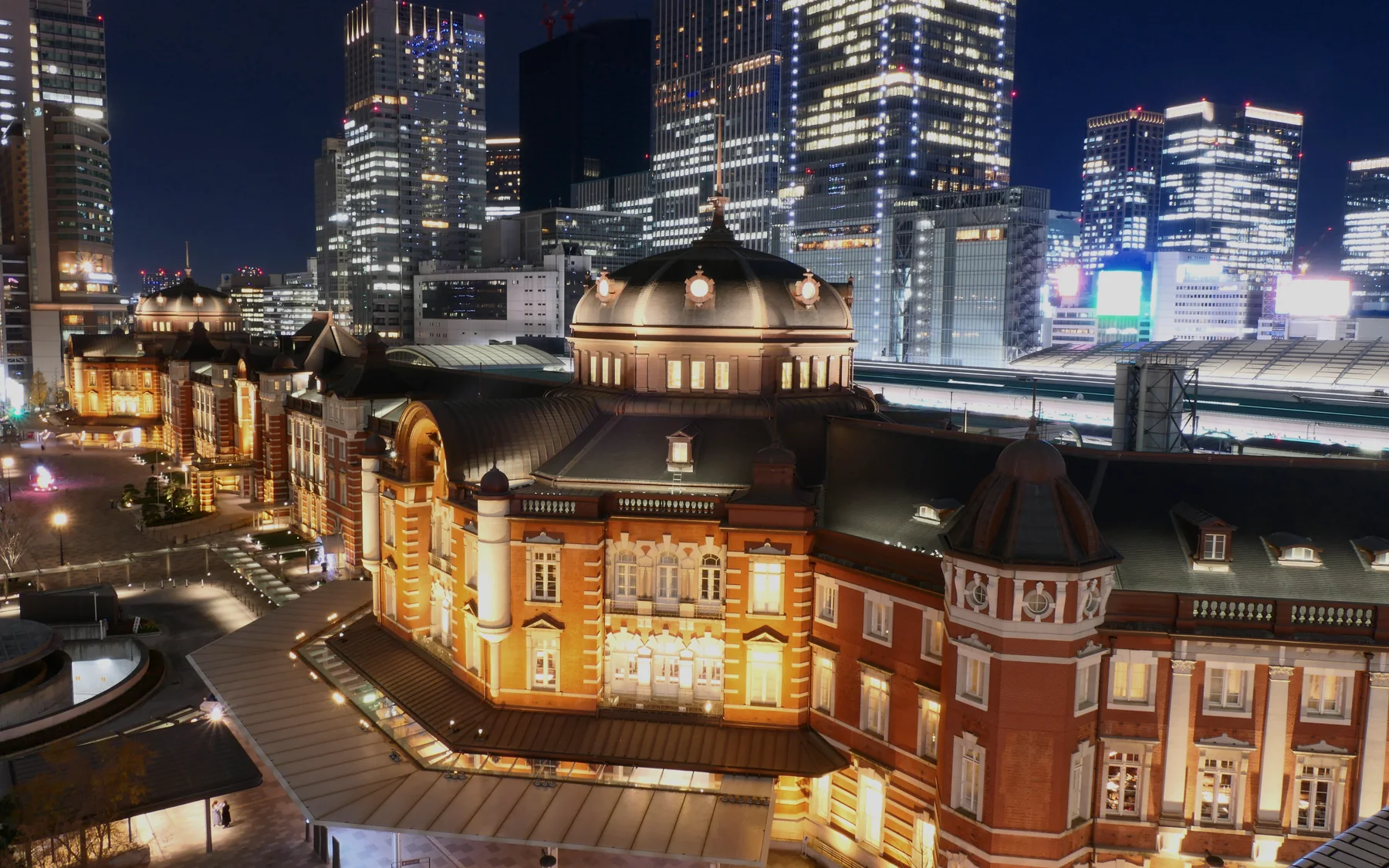 Tokyo Station’s illuminated red-brick Marunouchi building against the modern night skyline.